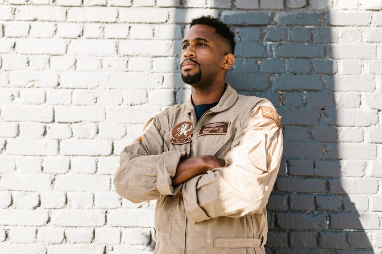 Featured Image Alt Text: Proud military veteran in uniform posing confidently against a brick wall background.